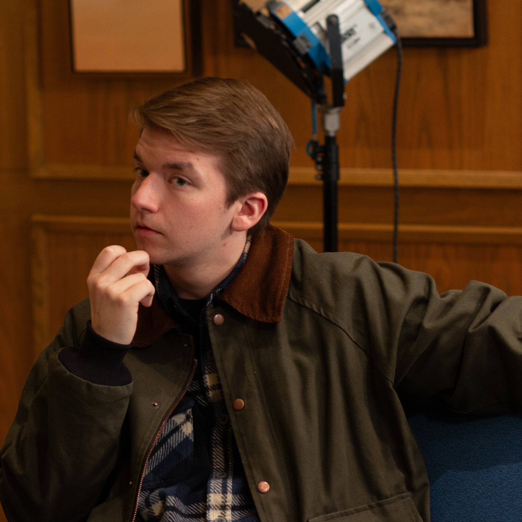side view of person with hand to chin and stage light in background